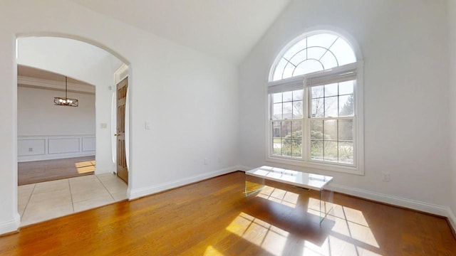 1904 Mullikin Dr, Champaign, IL 61822 - empty room featuring wood finished floors, lofted ceiling, a decorative wall, arched walkways, and an inviting chandelier