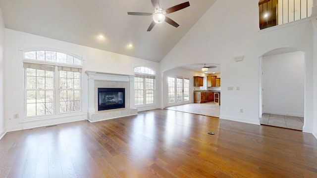 1904 Mullikin Dr, Champaign, IL 61822 - unfurnished living room featuring high vaulted ceiling, a tile fireplace, light wood-style flooring, arched walkways, and ceiling fan