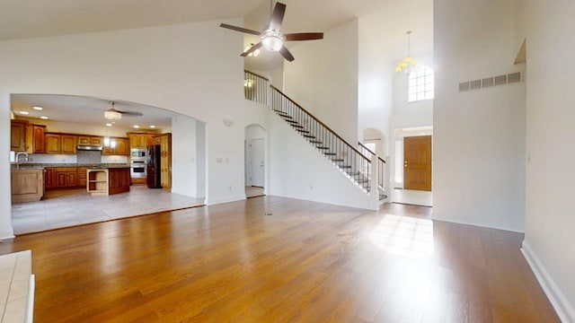 1904 Mullikin Dr, Champaign, IL 61822 - unfurnished living room featuring light wood-style flooring, visible vents, stairs, a ceiling fan, and arched walkways