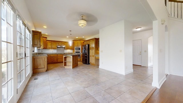 1904 Mullikin Dr, Champaign, IL 61822 - kitchen with open shelves, brown cabinetry, under cabinet range hood, stainless steel appliances, and arched walkways