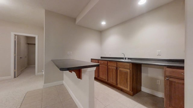 1904 Mullikin Dr, Champaign, IL 61822 - kitchen featuring brown cabinets, dark countertops, a kitchen bar, and a sink