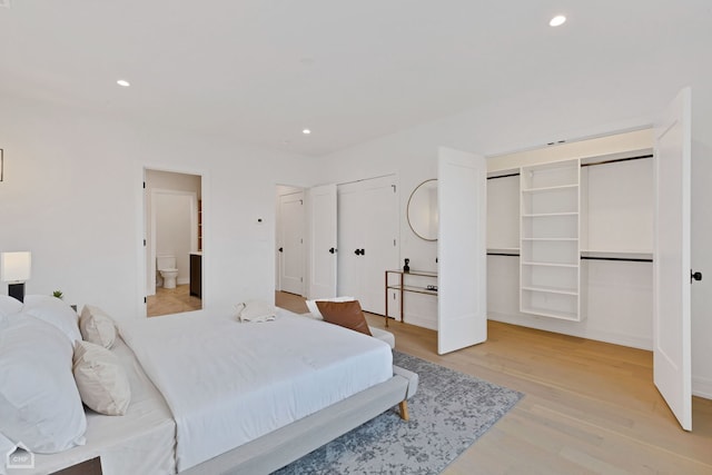 bedroom with recessed lighting, light wood-style floors, and multiple closets