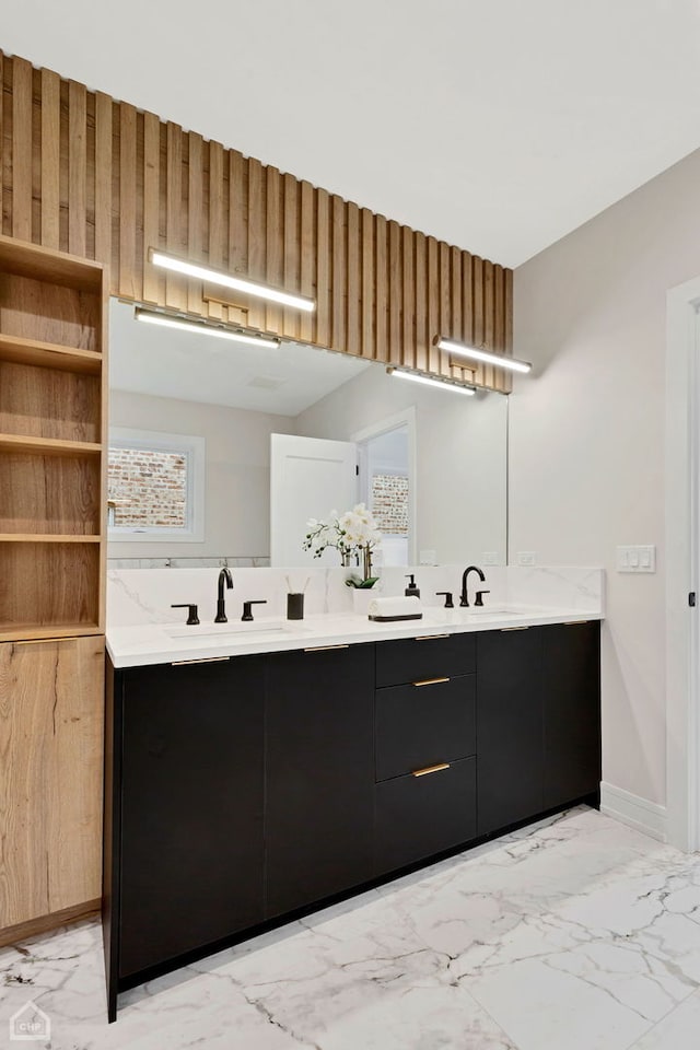 bathroom with double vanity, baseboards, marble finish floor, and a sink