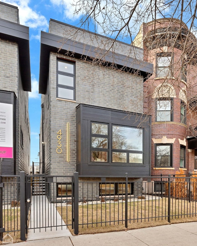 view of front facade featuring a fenced front yard, brick siding, and a gate