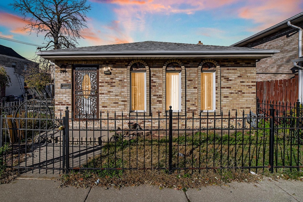 7624 W 61st St, Summit, IL 60501 - bungalow-style home featuring brick siding, a shingled roof, and a fenced front yard