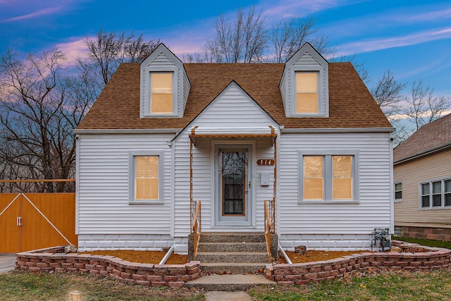 cape cod home with entry steps, roof with shingles, and fence