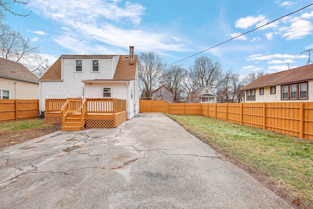 rear view of property featuring a deck, a patio, a fenced backyard, and a chimney