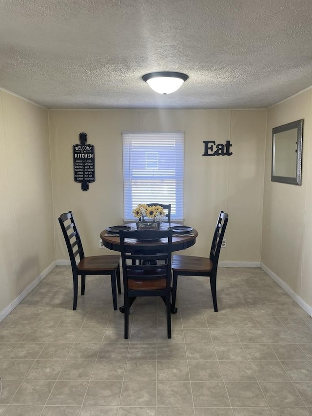 dining space featuring a textured ceiling and baseboards