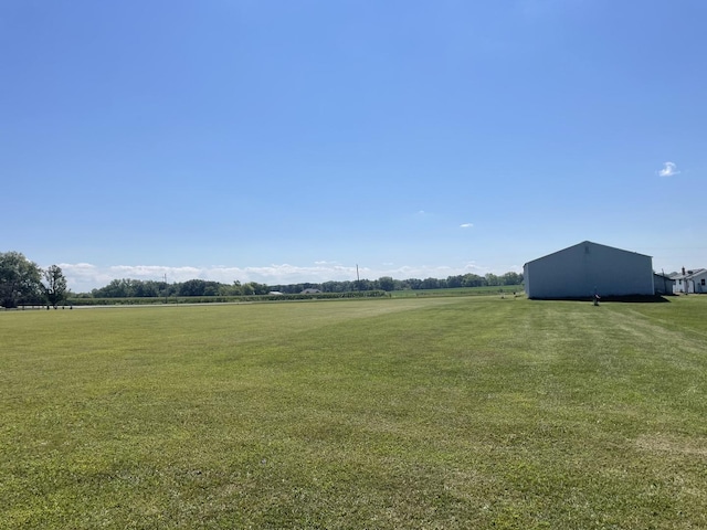 view of yard featuring an outbuilding, an outdoor structure, and a rural view