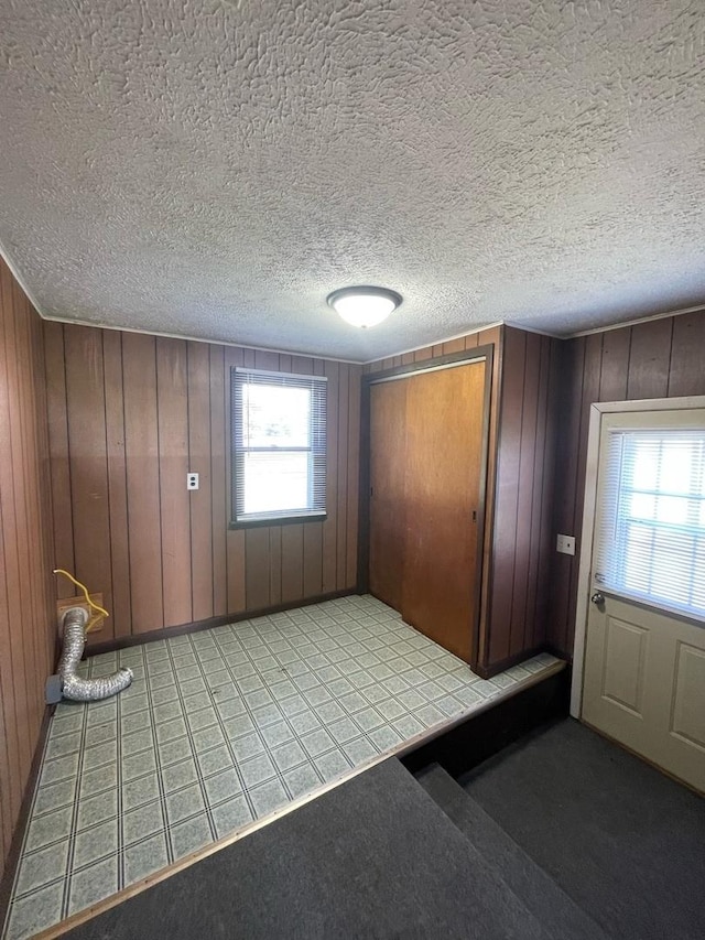 entrance foyer featuring light carpet, wood walls, and a textured ceiling