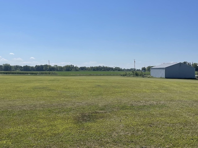 view of yard featuring a rural view, an outdoor structure, and a pole building