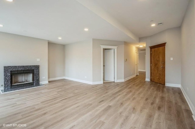 unfurnished living room with visible vents, recessed lighting, light wood-style floors, a premium fireplace, and baseboards