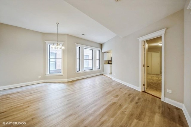 unfurnished living room with baseboards, light wood-type flooring, and a chandelier