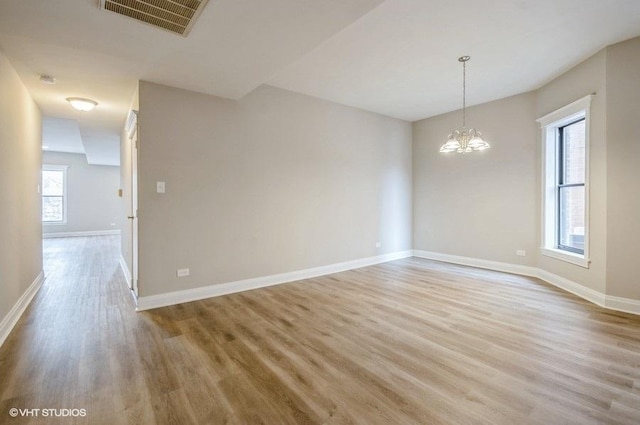 unfurnished room with a chandelier, visible vents, light wood-style flooring, and baseboards