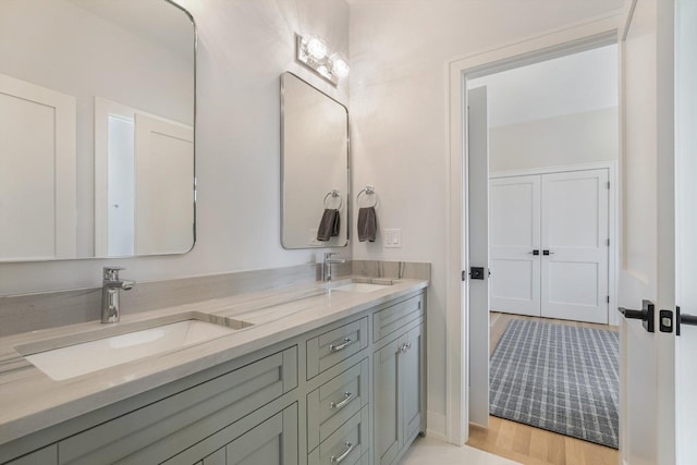 full bath with a sink, wood finished floors, and double vanity