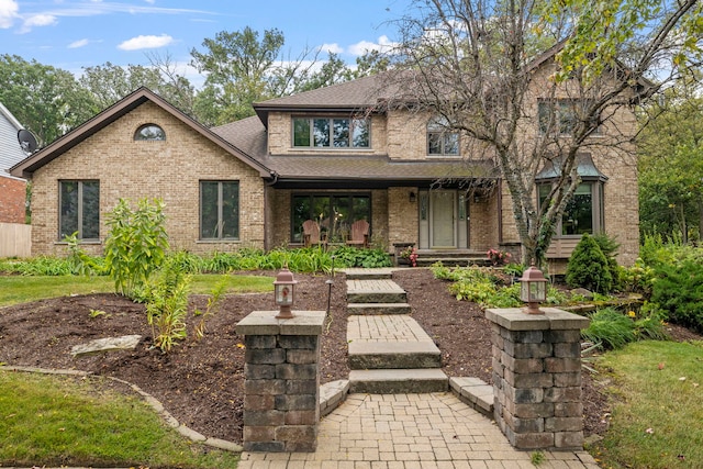 view of front facade with brick siding and a shingled roof