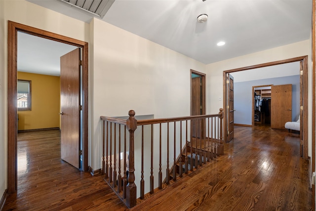 corridor featuring an upstairs landing, baseboards, and wood finished floors