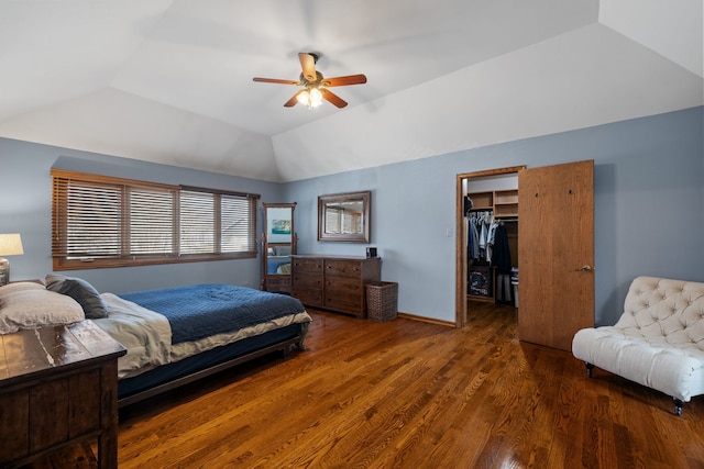 bedroom with a ceiling fan, wood finished floors, baseboards, a spacious closet, and vaulted ceiling