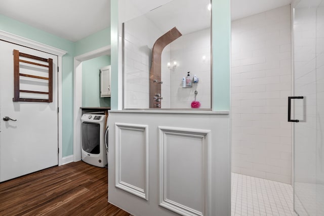 full bath featuring washer / dryer, wood finished floors, and a shower stall