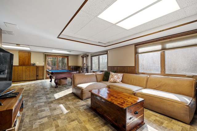 living area with wooden walls, a wainscoted wall, a drop ceiling, pool table, and stone finish flooring