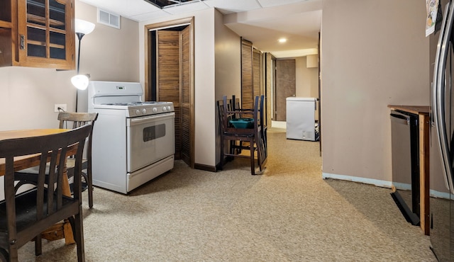 kitchen featuring visible vents, baseboards, light colored carpet, white gas range oven, and fridge