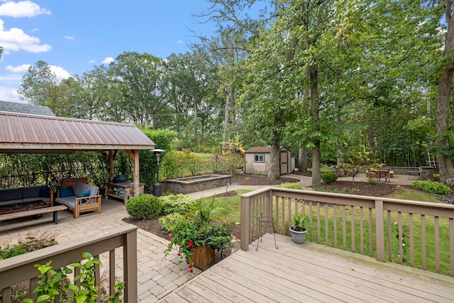 deck with a patio, a shed, a garden, an outdoor structure, and a fire pit