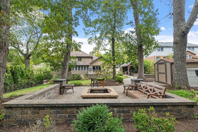 view of patio with an outbuilding, a shed, an outdoor fire pit, and fence