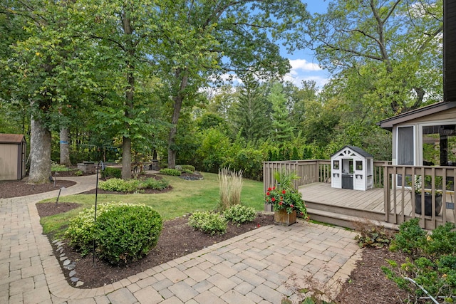 view of patio with an outbuilding, a wooden deck, and a storage unit