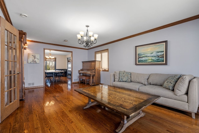 living area featuring baseboards, a notable chandelier, wood finished floors, and crown molding