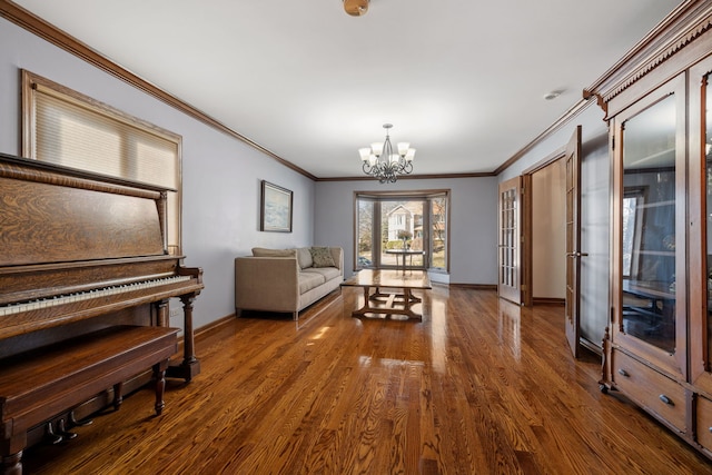 sitting room with a chandelier, dark wood-style floors, baseboards, and ornamental molding