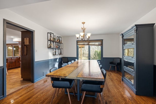 dining area featuring a wainscoted wall, an inviting chandelier, and wood finished floors