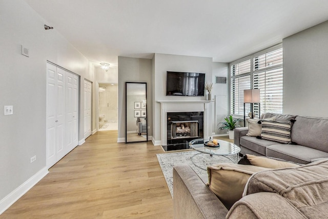 living room with visible vents, baseboards, light wood-style flooring, and a fireplace