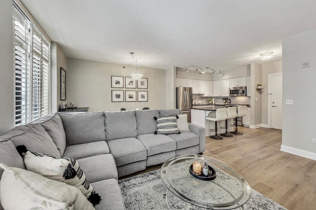 living room with baseboards, track lighting, and light wood finished floors