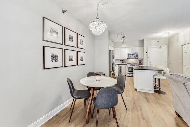 dining room featuring baseboards, light wood-type flooring, and an inviting chandelier