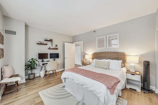 bedroom with light wood finished floors, visible vents, and baseboards