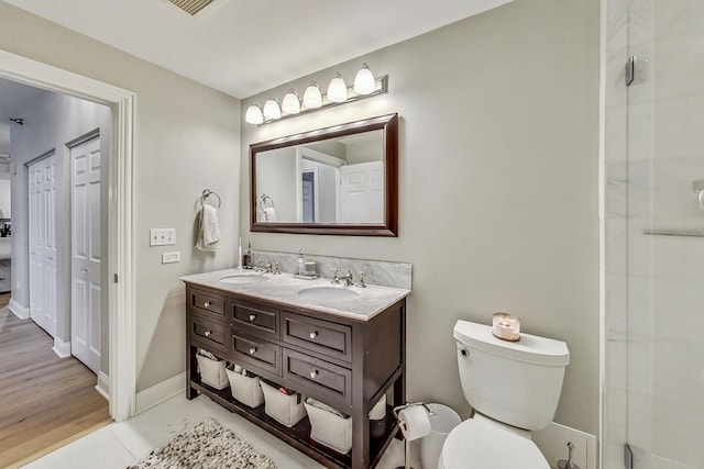 full bath featuring a sink, baseboards, toilet, and double vanity