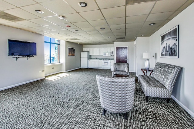 unfurnished living room with visible vents, baseboards, dark colored carpet, and a drop ceiling