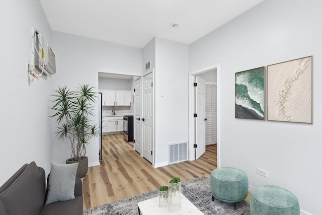 corridor featuring visible vents, light wood-type flooring, and baseboards