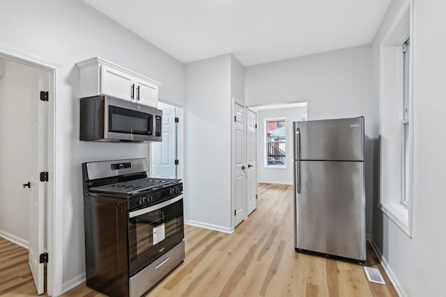 kitchen featuring stainless steel appliances, white cabinetry, baseboards, and light wood finished floors