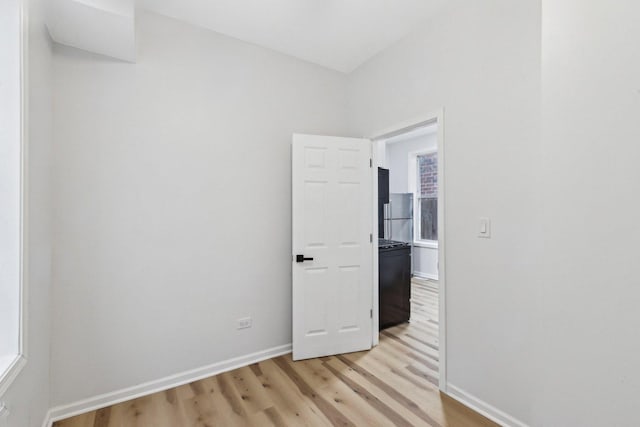 spare room featuring baseboards and light wood finished floors