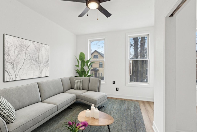 living area with baseboards, ceiling fan, and wood finished floors