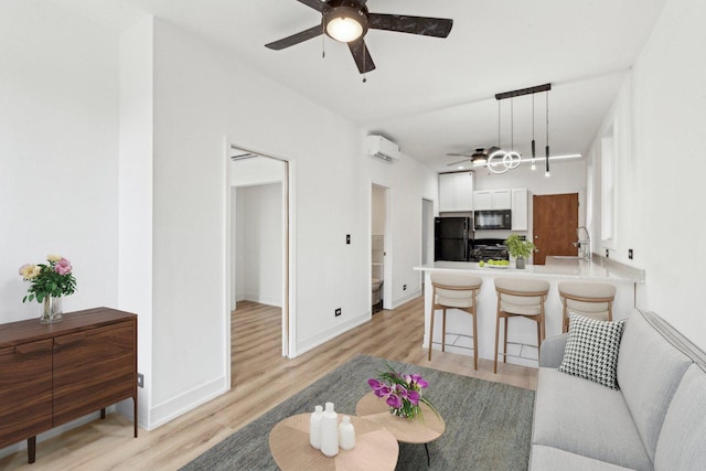 living room featuring a ceiling fan, light wood-type flooring, a wall mounted air conditioner, and baseboards