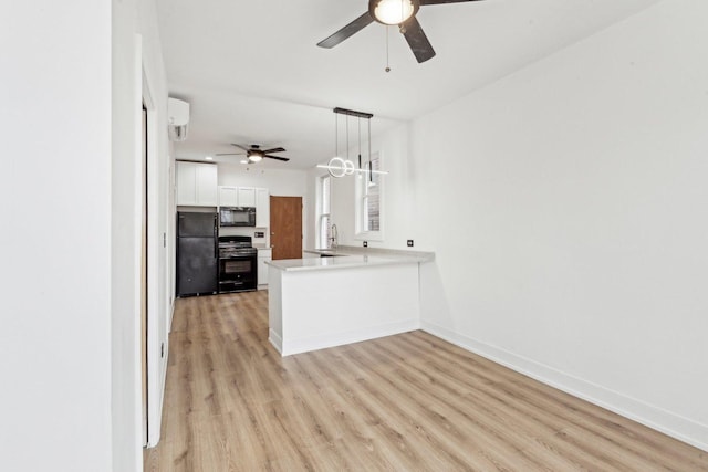 kitchen featuring light wood finished floors, a peninsula, white cabinets, black appliances, and a ceiling fan