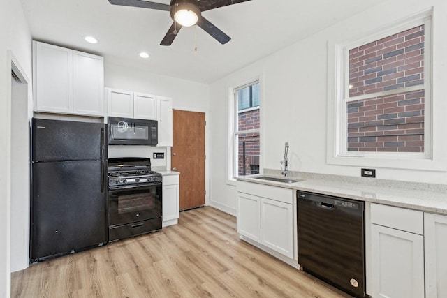 kitchen featuring black appliances, light wood-style flooring, a sink, white cabinets, and ceiling fan