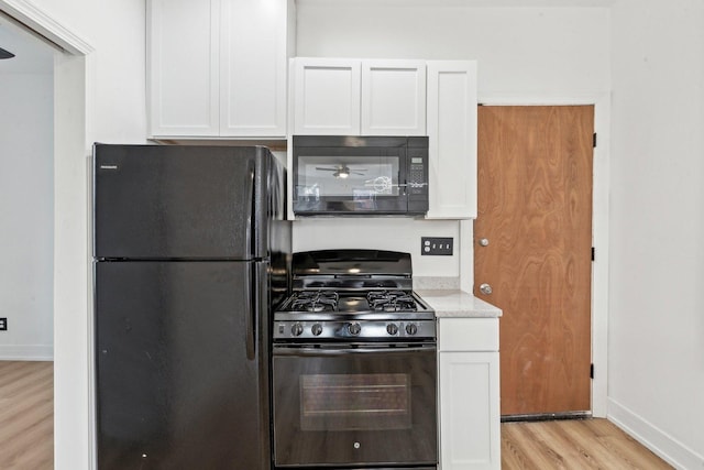 kitchen featuring white cabinetry, black appliances, light wood-style floors, and baseboards