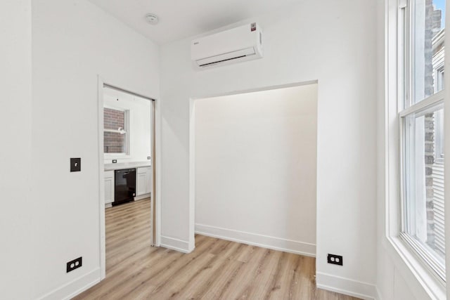 empty room featuring baseboards, light wood-style floors, and an AC wall unit