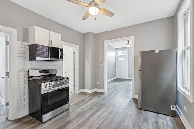 kitchen with wood finished floors, a ceiling fan, a wealth of natural light, and stainless steel appliances