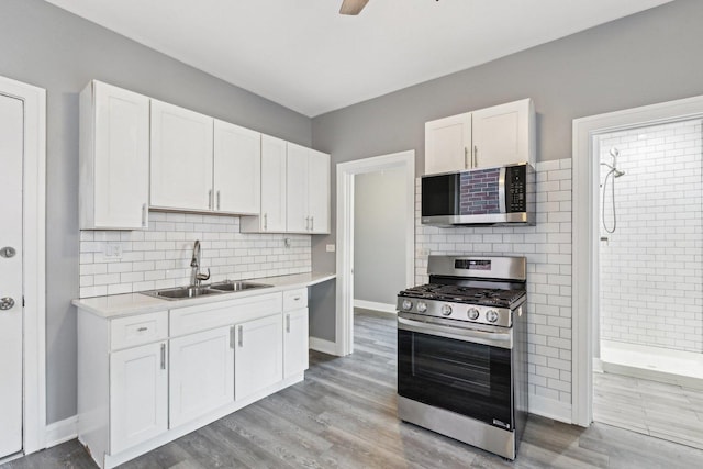 kitchen featuring a sink, light countertops, white cabinets, appliances with stainless steel finishes, and light wood-type flooring