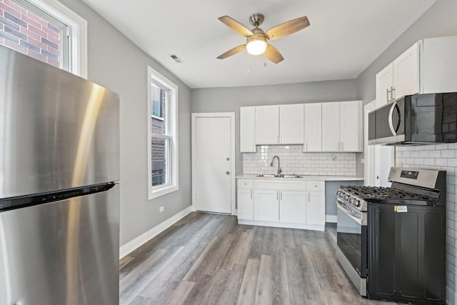 kitchen with visible vents, a sink, backsplash, appliances with stainless steel finishes, and ceiling fan