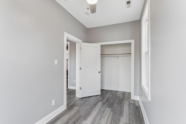 unfurnished bedroom with a ceiling fan, wood finished floors, visible vents, baseboards, and a closet